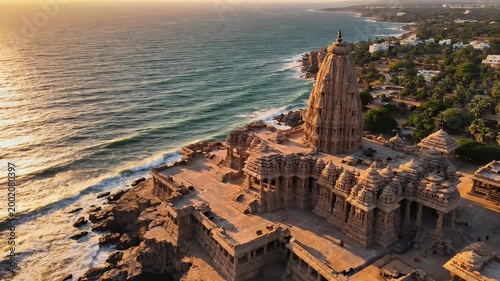 An aerial view showcases the stunning architecture of the Shore Temple in Mahabalipuram, India, dramatically perched on a rocky coastline with the turquoise ocean stretching into the horizon.