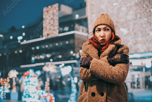 Foto Woman feeling cold and uncomfortable while standing outdoors in a city at night,