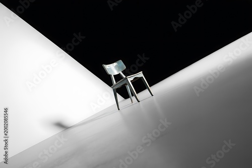 A single wooden chair standing in a modern room with dramatic light and shadow