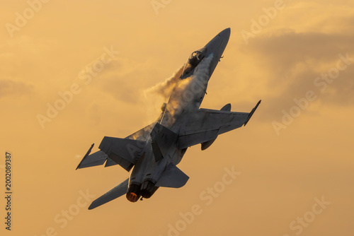 Photography Avión de combate  en maniobra de ascenso vertical con postcombustión y vapor al amanecer