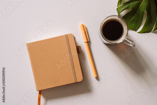 Notebook with pen and coffee in soft natural light.