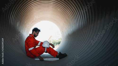 Fotografie Industrial Workers in Safety Gear Working Inside a Large Steel Pipeline During Oil and Gas Infrastructure Construction at an Industrial Facility