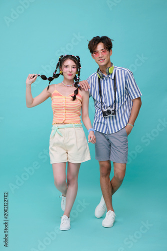 Asian couple posing with camera and headphones stylish young travelers enjoying leisure lifestyle summer fashion tourism experience modern youth culture concept