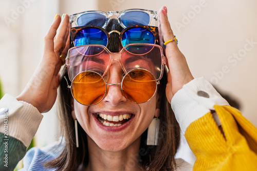 A girl is wearing a lot of sunglasses and is having fun. A girl is having fun in a sunglasses store. Fun and madness.