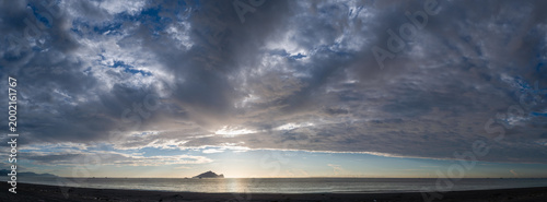 A panoramic view of the sunrise over the Pacific Ocean, featuring the iconic Guishan Island silhouette under a dramatic cloudy sky in Zhuangwei, Taiwan.