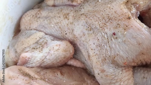 Raw marinated chicken in a saucepan with pepper and salt. Grilled Chicken Roasting Process