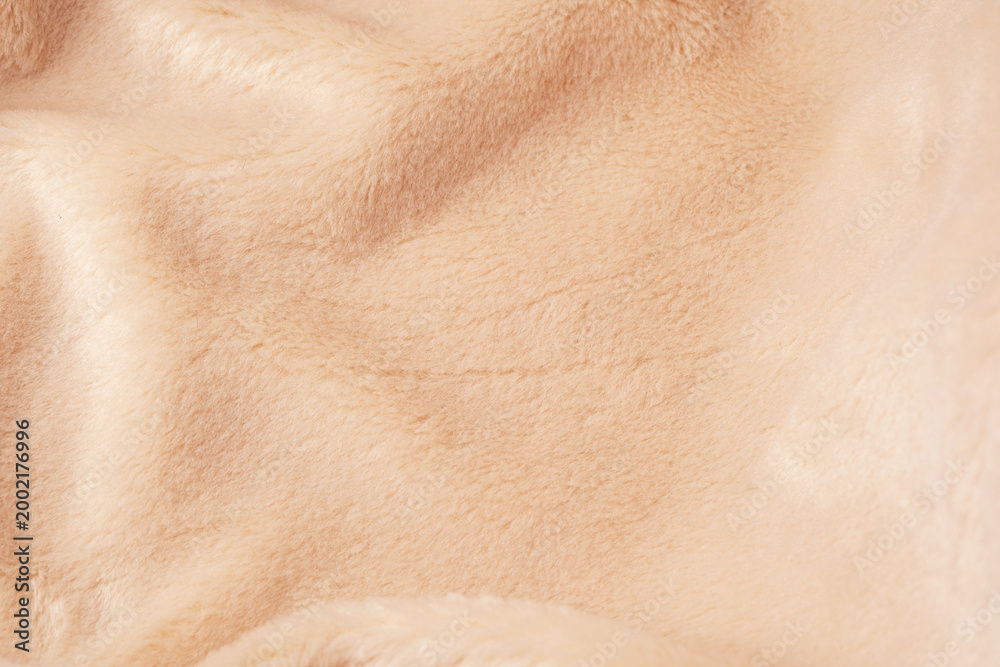 Fototapeta premium Detailed view of warm soft beige fluffy textile material showing subtle folds and shadows
