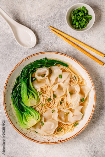 Warm noodle soup with dumplings (wontons) and cabbage bok choy
