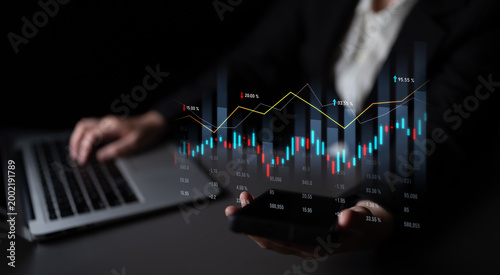 A professional examines financial data displayed on a tablet in one hand, with a laptop on the table, showcasing modern business analytics in a sleek workspace. Scalp