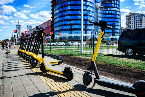Electric scooters are parked in the city center. Public mobile transport stand outside.
