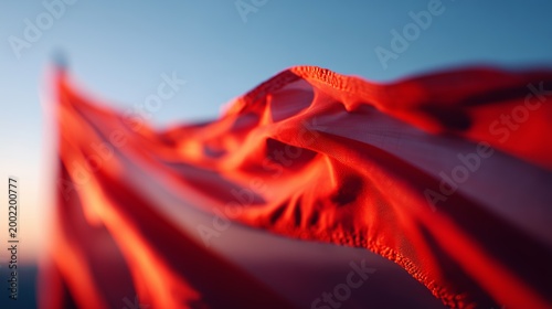 Close-up of a red flag gently waving, captured against a clear dusk sky, evoking movement and freedom.