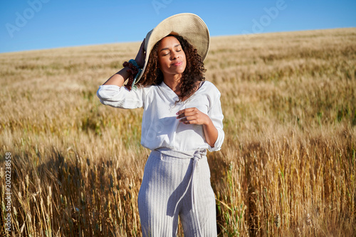 Woman enjoying sunshine in golden wheat field