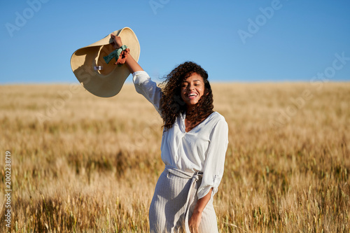 Happy young woman laughing in golden wheat field