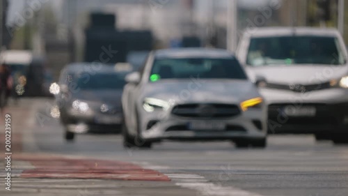Defocused low angle view of dense city traffic approaching camera, abstract motion of vehicles with heat haze and shimmering air above asphalt, bright sunny day urban scene