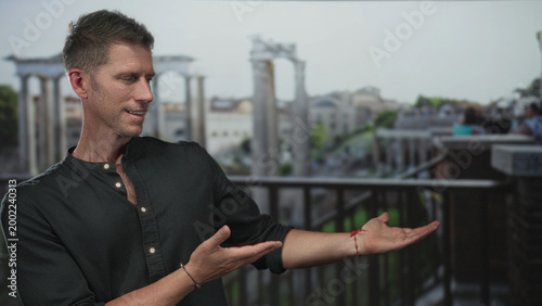 Photography Man giving thumbs up on a balcony at roman ruins with ancient columns and railing; confidence travel history exploration