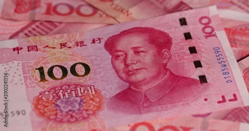 red Chinese money in denominations of one hundred yuan and American dollars , a pile of paper cash of American and Chinese money , Chinese banknotes of 100 yuan