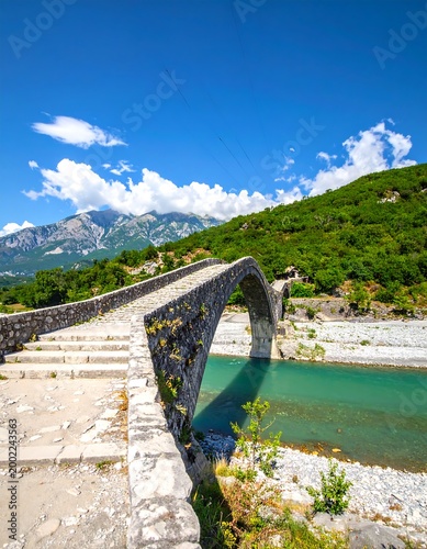 Ancient stone bridge arches over a clear turquoise river