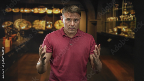 Tableau sur toile Man pointing finger at display case in museum gallery while gesturing with open palm to emphasize a claim; concern accusation