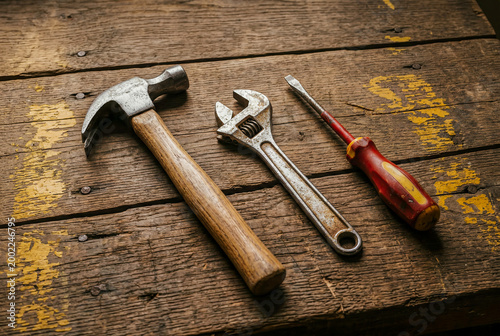 Vintage Hammer Wrench and Screwdriver Hand Tools on Distressed Wooden Workbench