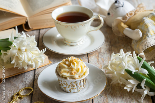 Photos Morning tea, small cakes and flowers on the table.