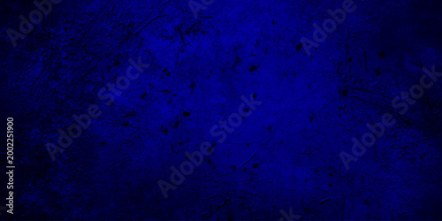 Dark blue grunge texture background with vignetting, abstract navy blue mottled wall surface