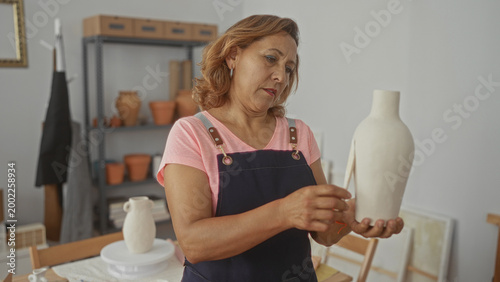 Foto Hispanic woman gently shapes ceramic vase with knife in studio wearing pink apron; artistic concentration