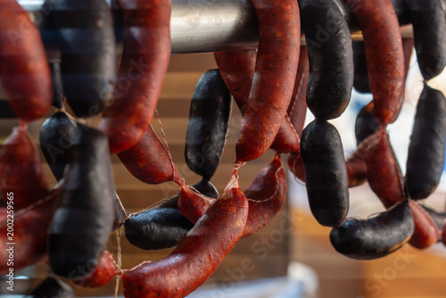 Foto Traditional cured red chorizo and dark blood sausages hanging in a Spanish deli or market