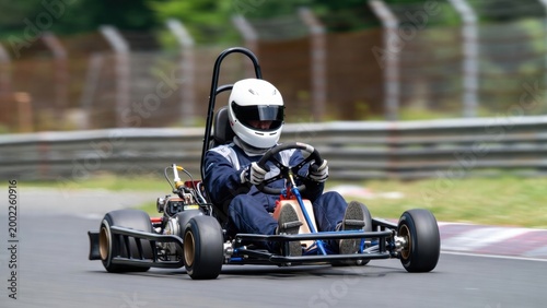 Go kart driver cornering on paved race circuit during practice session