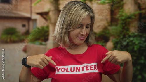 Cuadro en lienzo Woman flexes arms in ancient roman building while wearing red volunteer shirt with bold text; pride service community