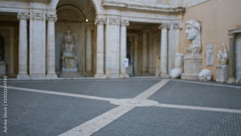 Obraz premium Classical museum courtyard with carved statues and colonnade, softly defocused; background backdrop copyspace calm.