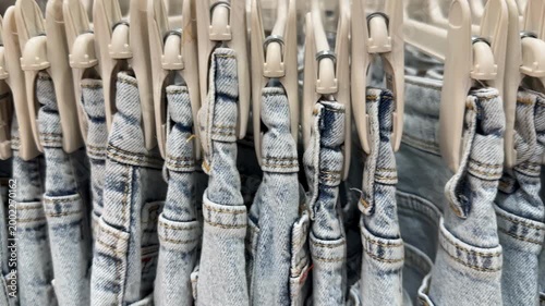 Denim jeans neatly hung on white clothes hangers, showcasing variety in a store display