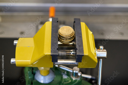 Obraz na plátně Euro coins clamped in a yellow metal vise