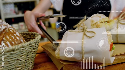 Server using tongs sliding lifting and placing wraps on bag for cafe display HUD overlaying hands