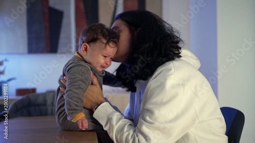 Photos Mother comforting fussy baby indoors, holding child gently while soothing during
