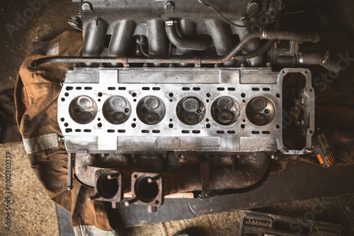 Fotografie Close-up view of a disassembled internal combustion engine cylinder head and man