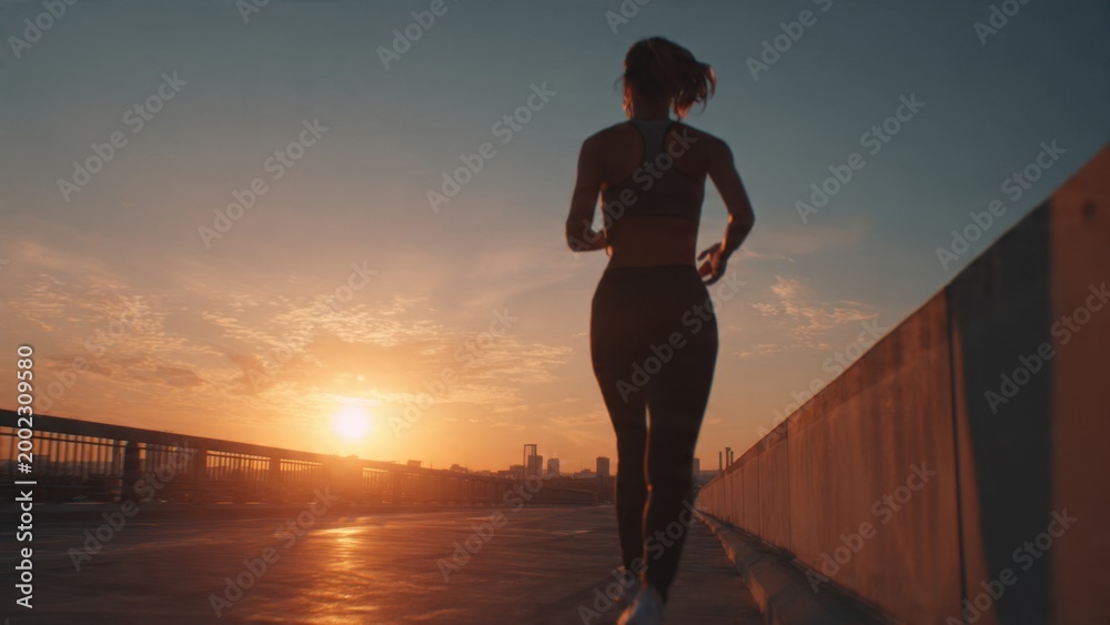 Fototapeta premium Woman Running at Sunset on Urban Bridge