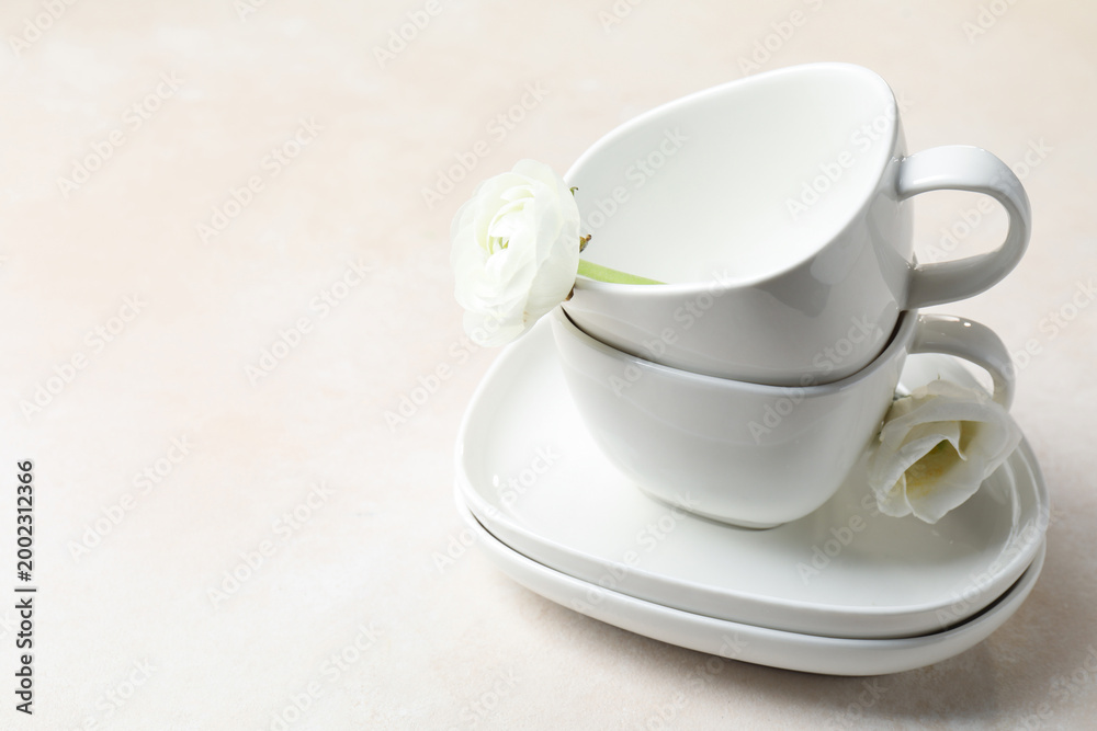 Fototapeta premium Porcelain tea set and beautiful flowers on light table. Space for text