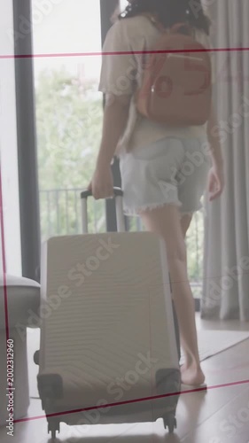Vertical video: Woman gripping handle, pulling suitcase toward balcony, red charts tracking travel