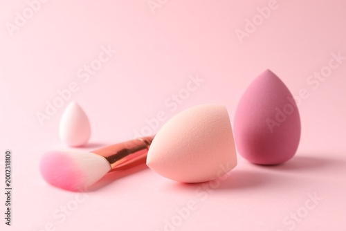 Fotografie Clean makeup sponges and brush on pink background, closeup