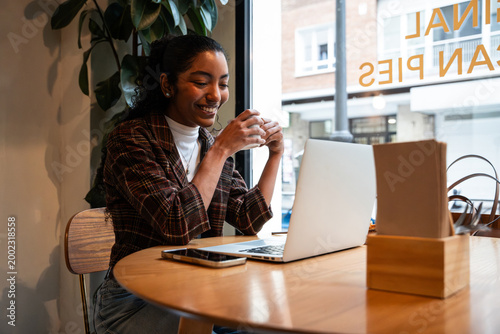 Young woman working on laptop in cafe with coffee break