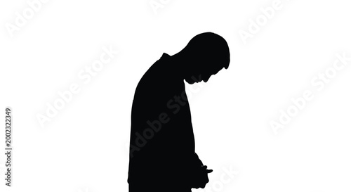 Silhouette of a man looking down with his head bowed in a thoughtful posture alone