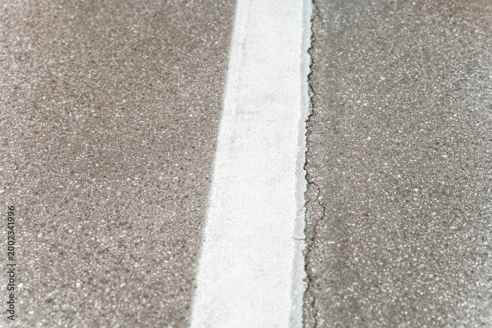 Obraz premium Top view of cracked asphalt road with white painted dividing line. Concept foto of the road.