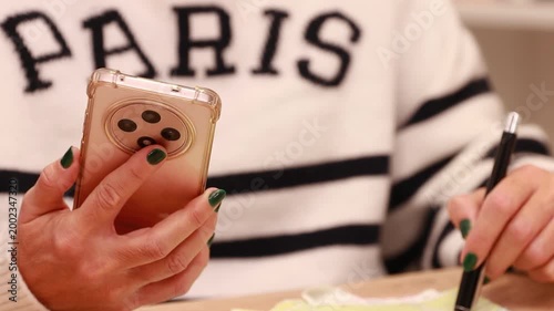 young woman's hands with a mobile phone reviewing the trip or itinerary on the map on the desk, wearing a Paris sweater