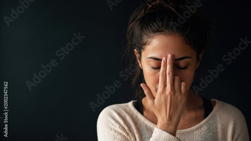 Young woman practicing alternate nostril breathing (Nadi Shodhana) for mindfulness and stress relief, pranayama yoga exercise on a dark background.