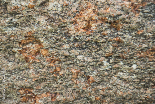Close-up of natural granite rock surface featuring orange mineral veins and rugged stone texture, perfect for abstract backgrounds, geology themes, and construction design use.