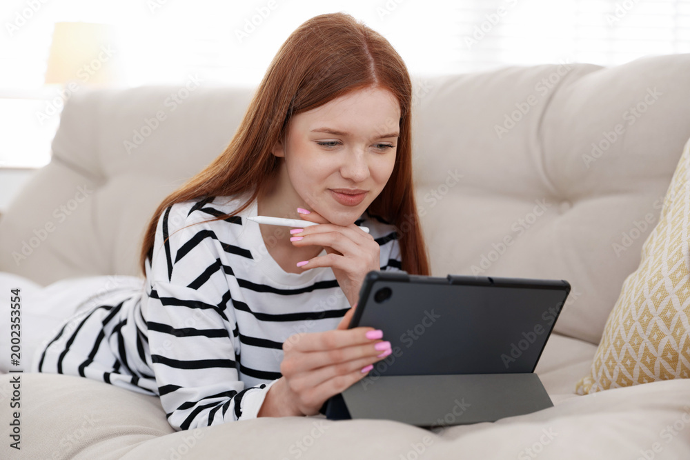 Fototapeta premium Teenage girl using tablet on sofa at home