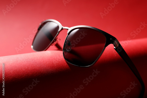 Tableau sur toile Pair of stylish sunglasses on red background, closeup