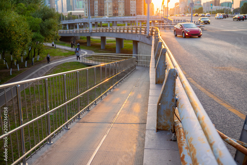 Metal wheelchair ramp outdoor for accessibility on pedestrian bridge. Infrastructure for city urban mobility. Equal opportunity entrance for disabled person with mobility aid in modern street.