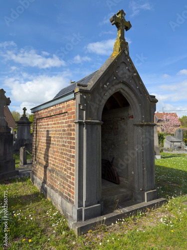 Brick chapel tomb with cross in sunny cemetery
