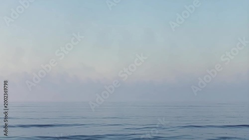 Calm ocean horizon with soft mist and gentle waves. Serene seascape background featuring a clear blue sky gradient and smooth water surface. Peaceful nature landscape concept.
